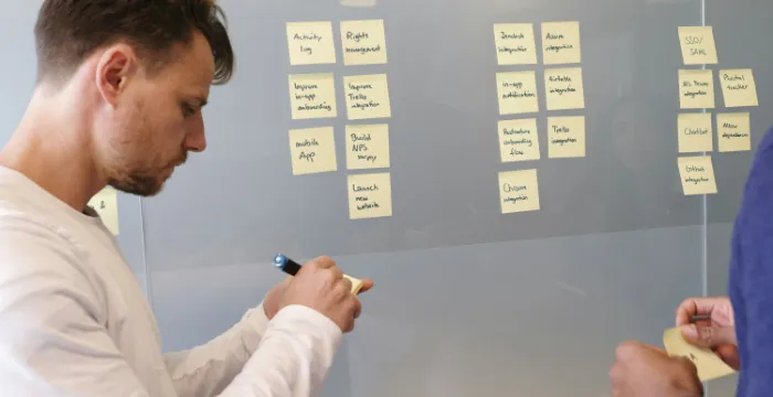 A person organizing tasks on a whiteboard with sticky notes, implementing the Pareto 80/20 rule for focused, sustainable productivity