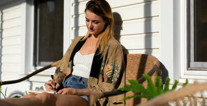 A person writing in a journal during a sunset, reconnecting with purpose and finding meaning to overcome emotional exhaustion after a burnout