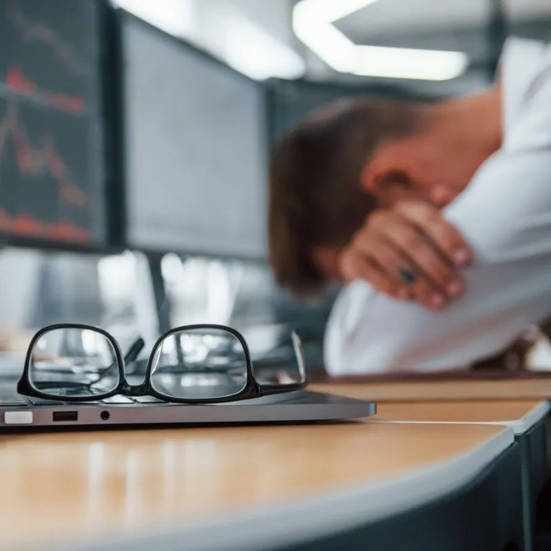 A visibly tired person resting their head on a desk next to a laptop, symbolizing the overwhelming feeling of burnout and mental fatigue
