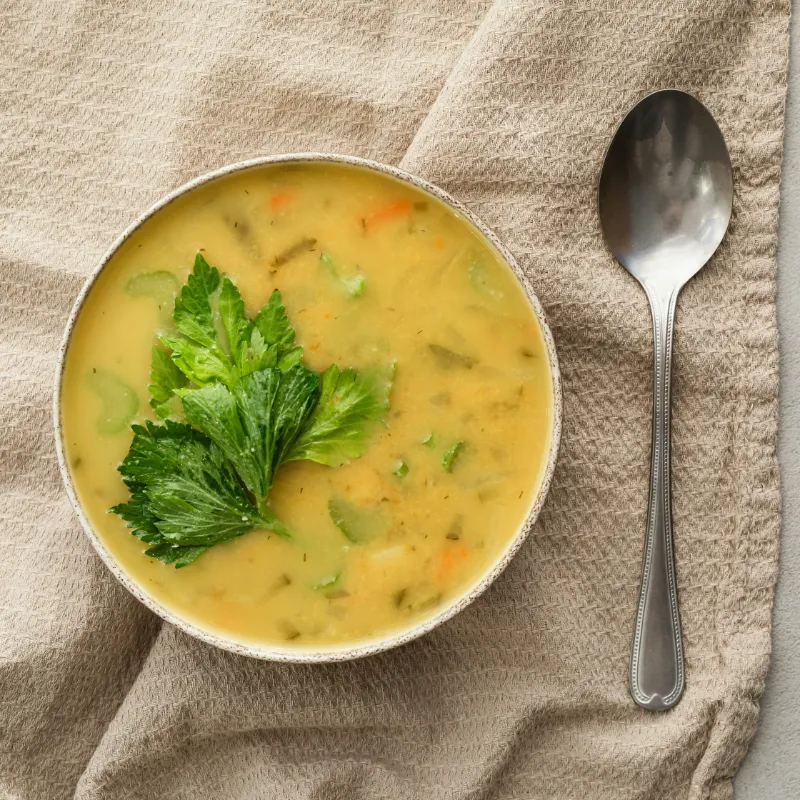 Bowl of hearty lentil and vegetable soup with a spoon, garnished with fresh parsley