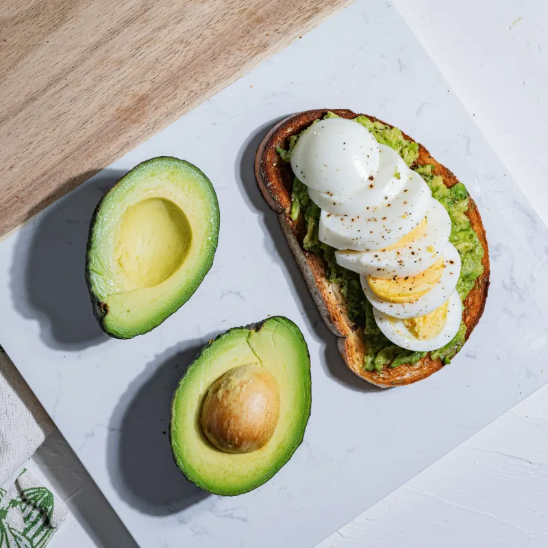 Healthy avocado toast topped with fried egg and chili flakes on whole-grain bread