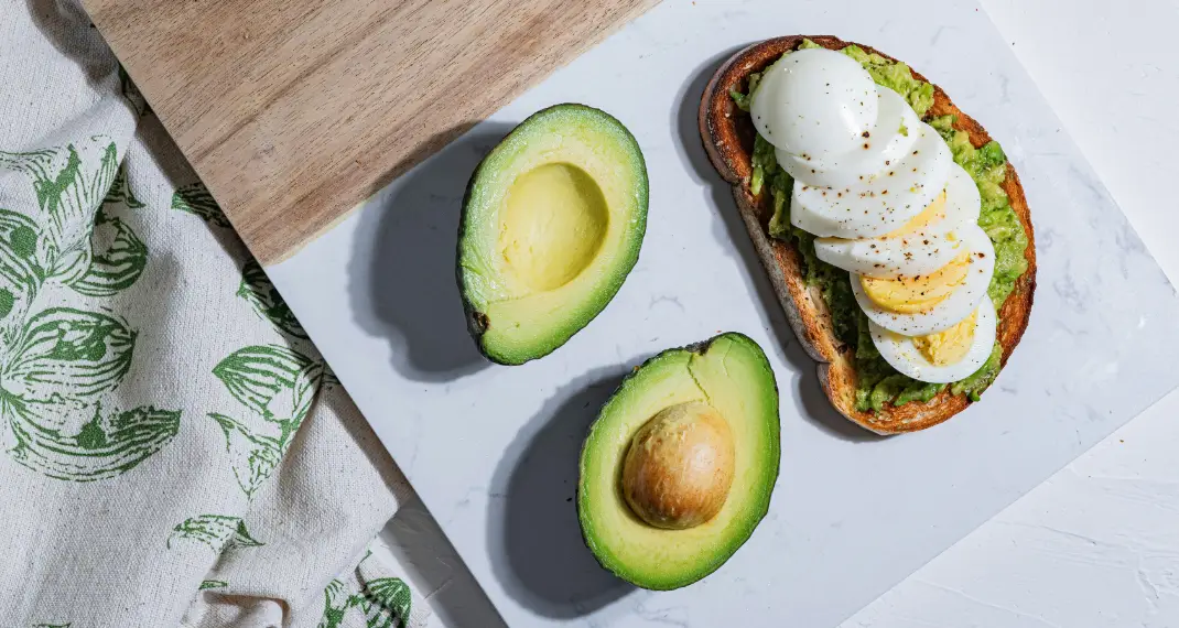 Healthy avocado toast topped with fried egg and chili flakes on whole-grain bread