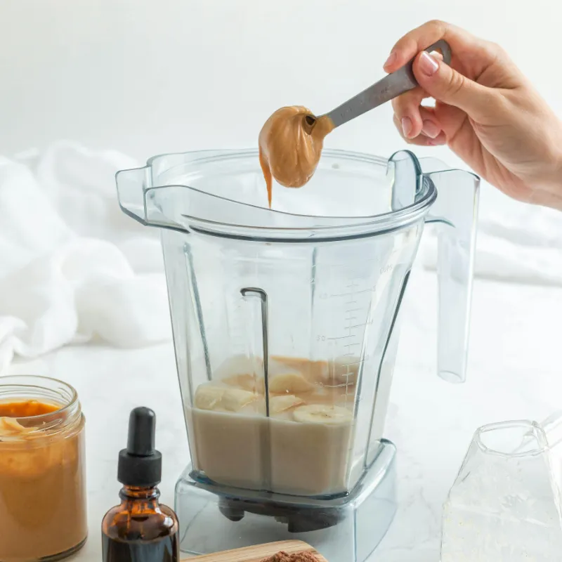 Banana peanut butter smoothie served in a glass with straw on wooden table