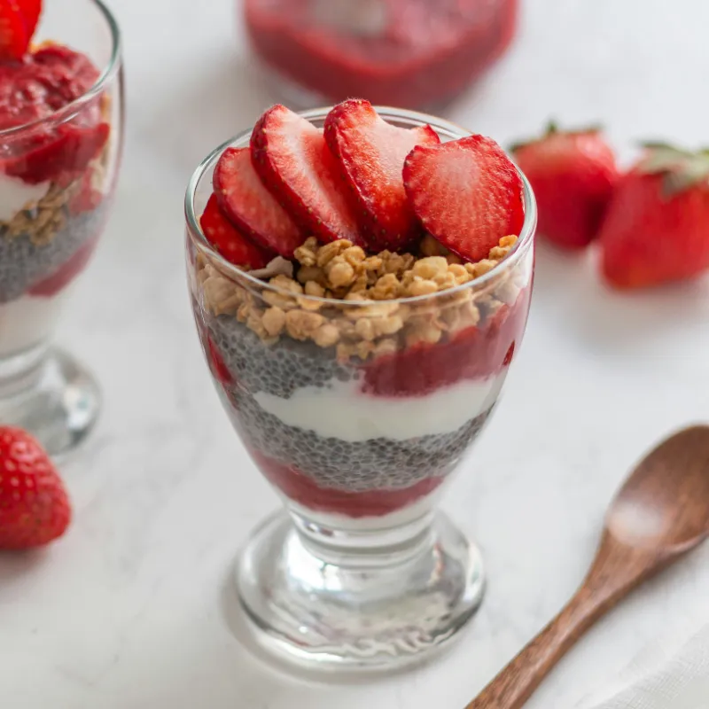 Greek yogurt parfait layered with fresh berries, granola, and honey in a glass