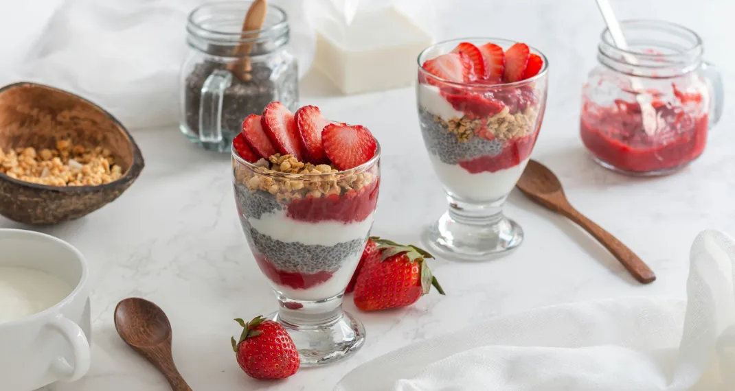 Greek yogurt parfait layered with fresh berries, granola, and honey in a glass