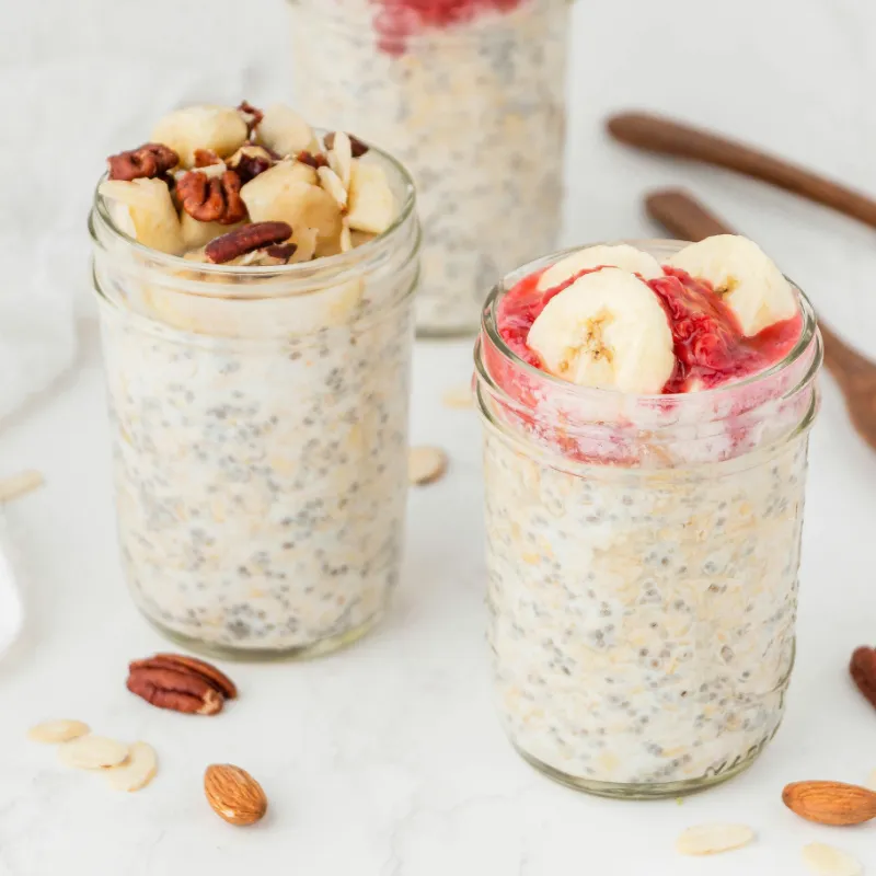 Overnight oats in a glass jar topped with fresh fruit and nuts on breakfast table