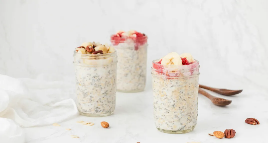 Overnight oats in a glass jar topped with fresh fruit and nuts on breakfast table